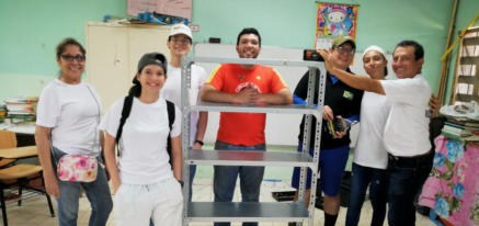 Voluntarios junto a la estantería terminada